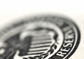 Very tightly cropped image of a dollar bill with selected focus on the Federal Reserve official symbol