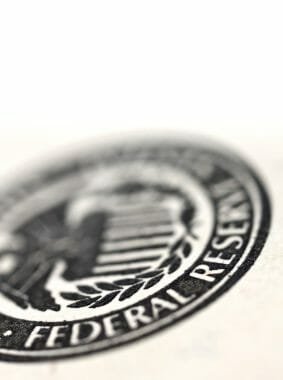 Very tightly cropped image of a dollar bill with selected focus on the Federal Reserve official symbol