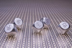 Metal dice with the currency symbols of Europe, England, United States, Russia, Japan, and China on a steel mesh background